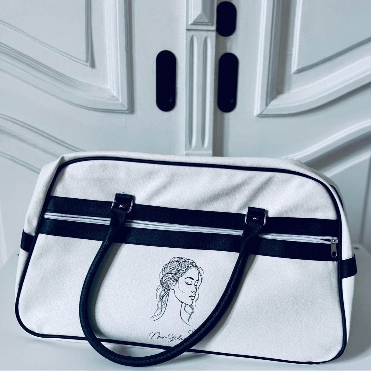 Schwarz-weiße Bowlingtasche mit dem Logo von NeuGeliebt. Im Hintergrund eine Tür.