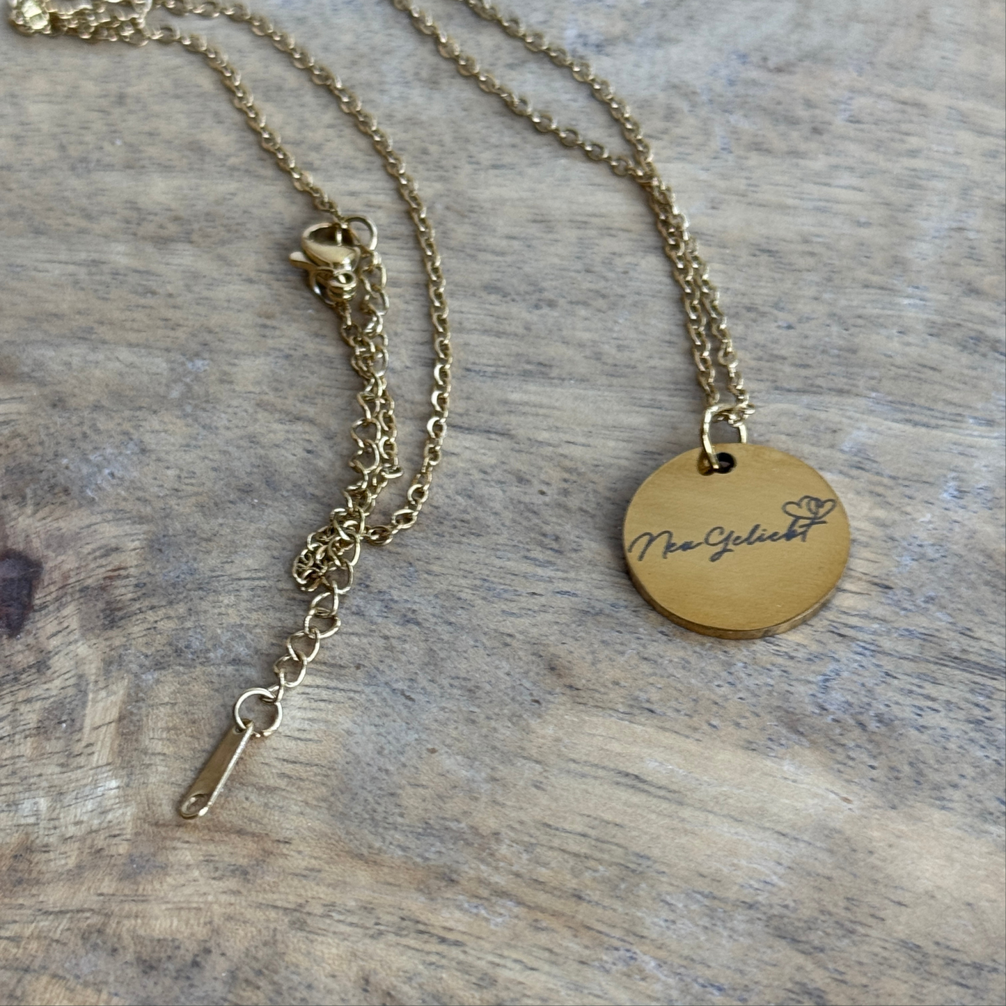 Anhänger mit Kette, goldfarben mit dem NeuGeliebt Logo.