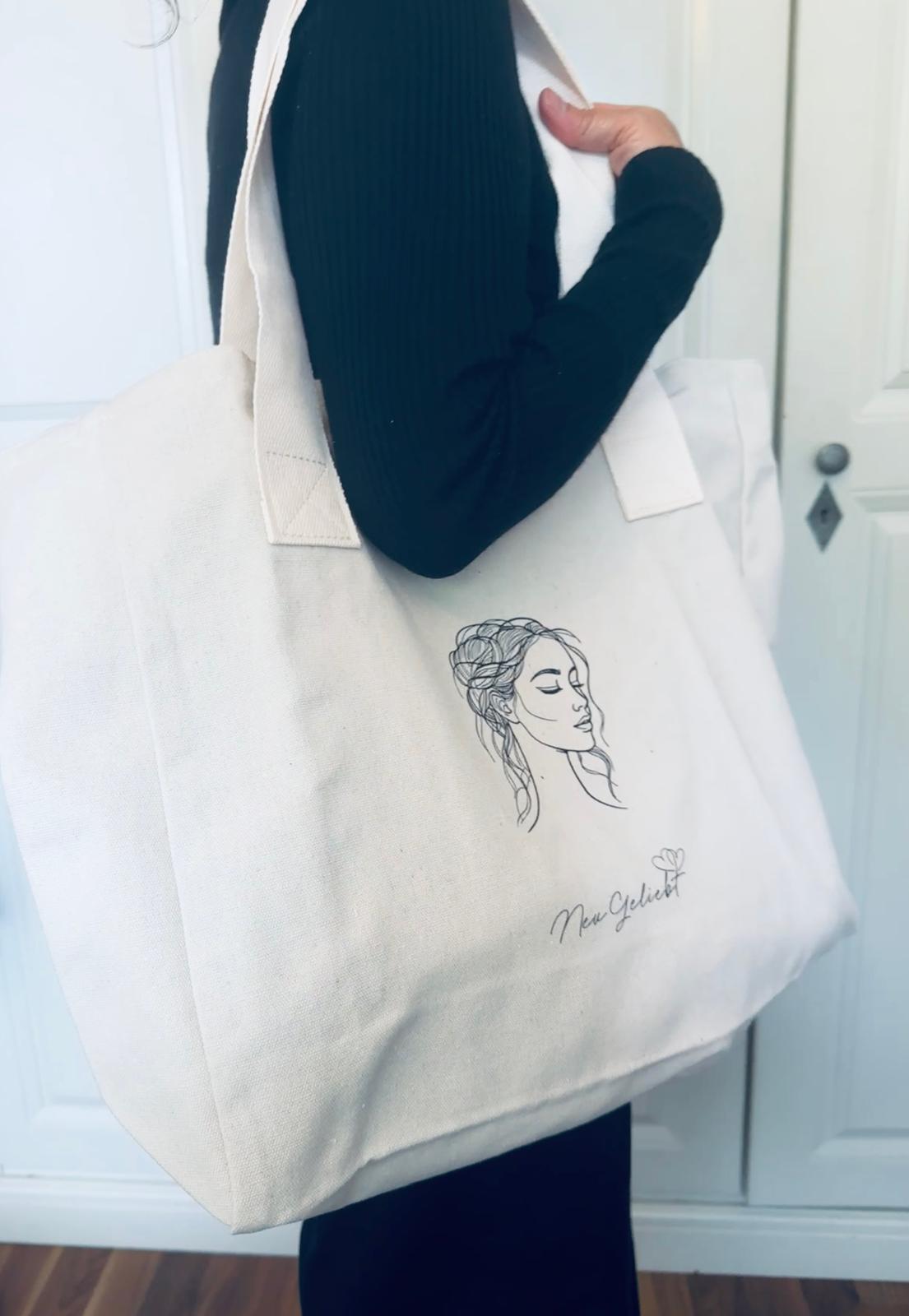 Ein Frau mit Beutel aus naturfarbenen Canvas mit Frauenkopf und Logo von NeuGeliebt.
