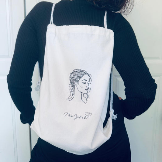 Frau mit weißem Rucksack aus Canvas mit Kordelzug.