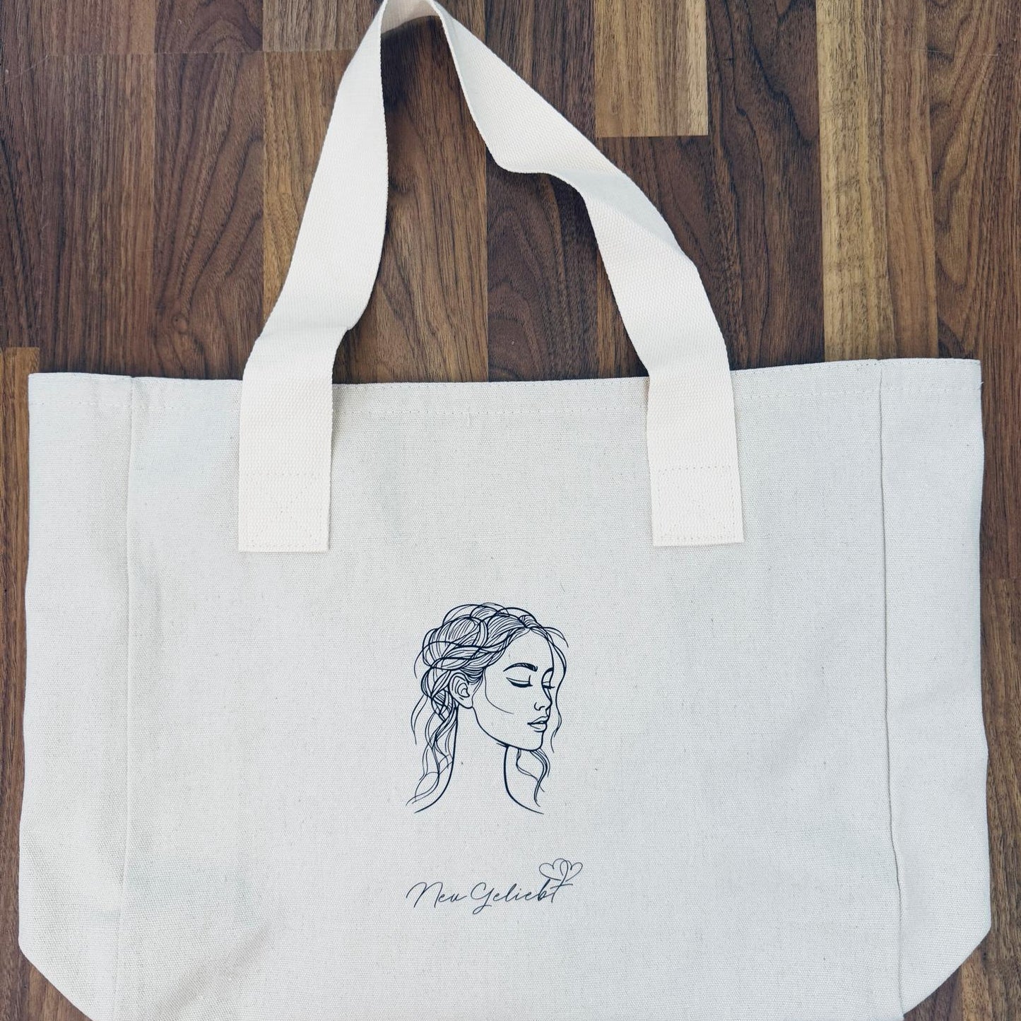 Ein Beutel aus naturfarbenen Canvas mit Frauenkopf und Logo von NeuGeliebt.