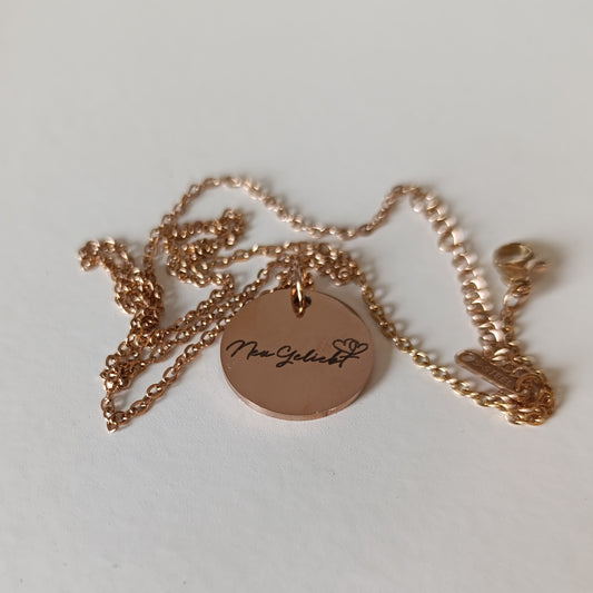 Roségoldfarbene Kette mit Anhänger vor weißem Hintergrund.