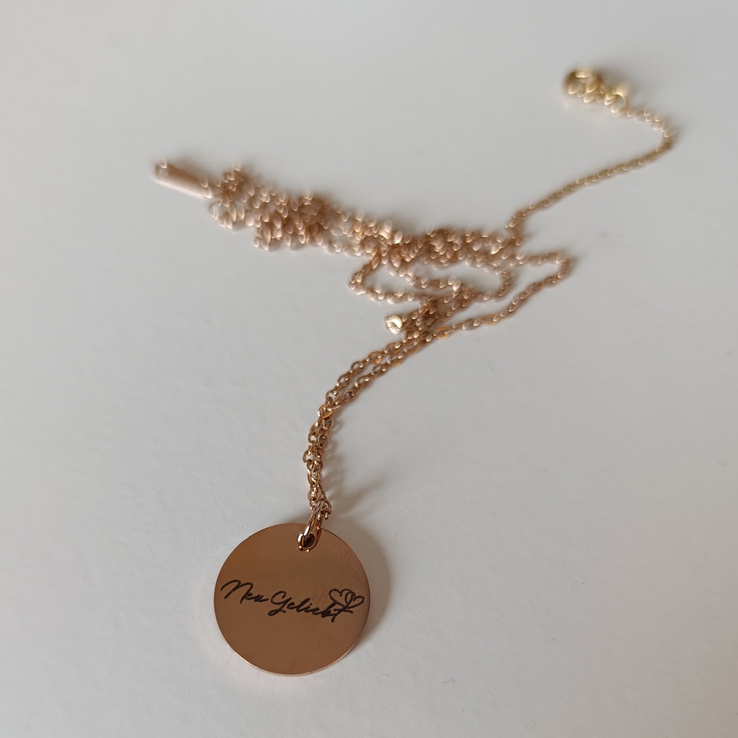 Roségoldfarbene Kette mit Anhänger Vorderseite mit NeuGeliebt-Logo vor weißem Hintergrund.