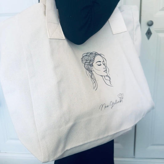 Ein Frau mit Beutel aus naturfarbenen Canvas mit Frauenkopf und Logo von NeuGeliebt.